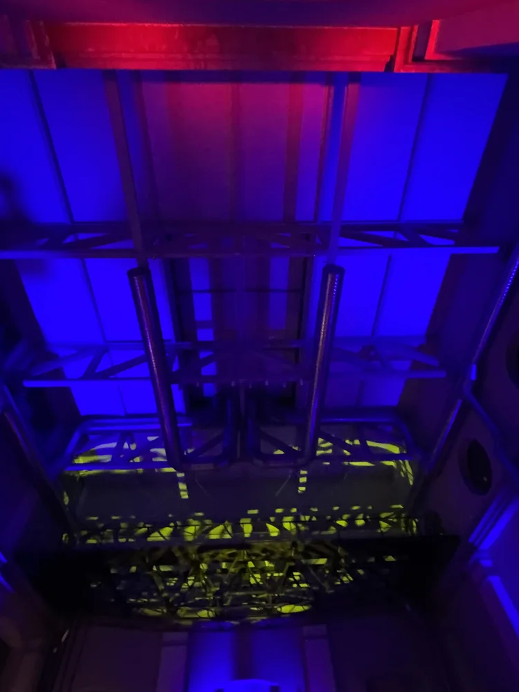 Soffitto della ex centrale termoelettrica di Daste e Spalenga — strutture industriali in acciaio rivelate da un lavaggio di luce blu con accenti rossi, composizione illuminotecnica SUONO E LUCE