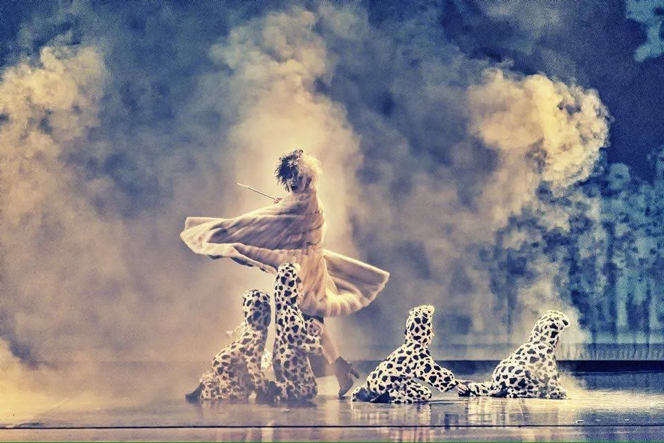 Danzatrice in controluce arancio con fumo scenico e danzatori a terra — coreografia di Giancarlo Poliseno, light design SUONO E LUCE