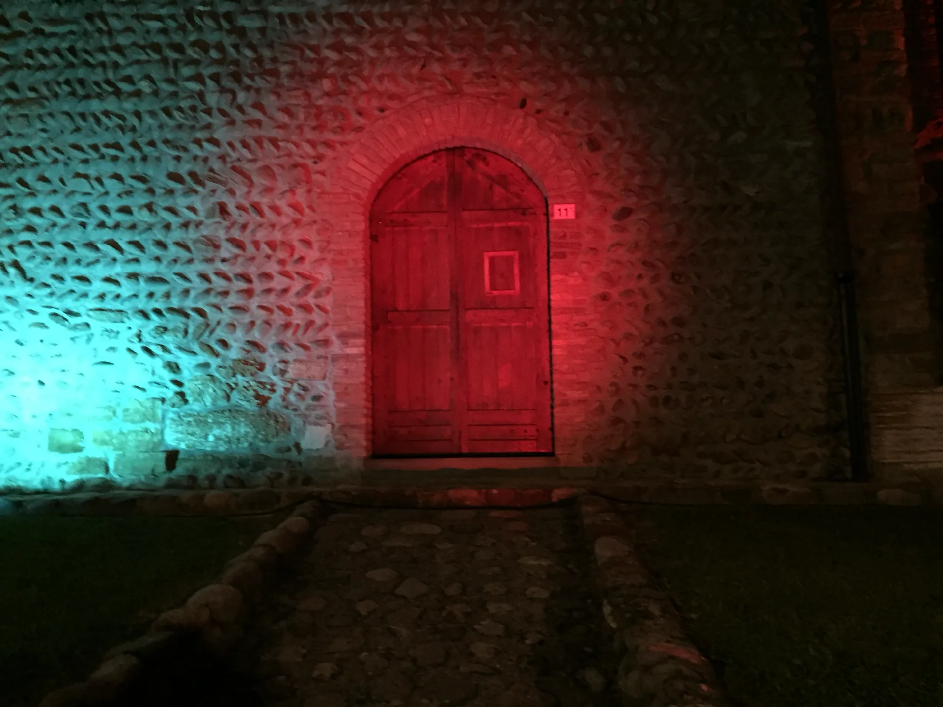 Portone antico del borgo di Rosciate illuminato in ciano e rosso — illuminazione architettonica SUONO E LUCE per la Festa del Moscato di Scanzo
