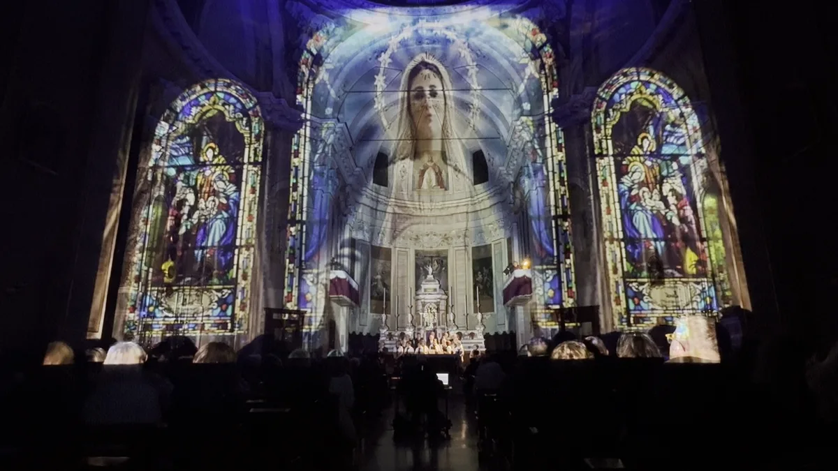 Madonna proiettata tra vetrate istoriate illuminate — edizione Luccicanti in una chiesa diversa, ogni edificio ha la sua voce, SUONO E LUCE